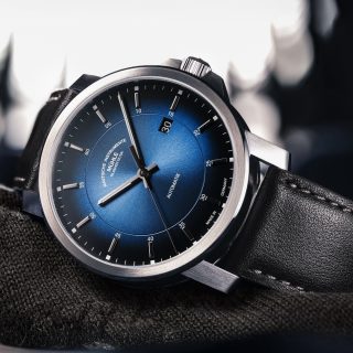 Armbanduhr 29er Casual Küstenblau am schwarzen Lederband liegt seitlich auf einem dunklen Stoff.