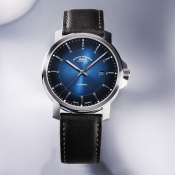 Frontalansicht der Armbanduhr 29er Casual Küstenblau am braunen Lederband auf einem weißen Tisch mit Schattenspiel.