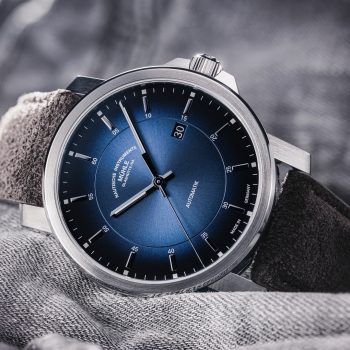 Armbanduhr 29er Casual am grauen Veloursband liegt seitlich auf einem grauen Stoff.