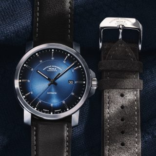 Armbanduhr 29er Casual Küstenblau am braunen Lederband liegt auf einem dunklen Untergrund, daneben ein graues Velourslederband.