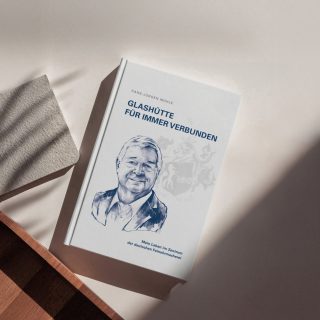 Buch "Biografie von Hans-Jürgen Mühle" liegt auf einem weißen Tisch, daneben ein kleines graues Heft.