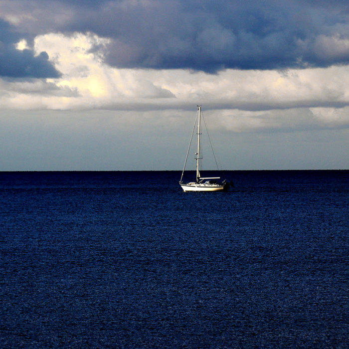 Moodbild ankerndes Segelboot allein auf weiter See