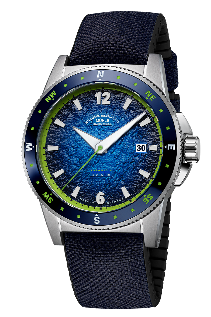 Sportivo Kompass Datum: Frontalansicht einer Armbanduhr mit blauem, strukturiertem Zifferblatt und grünen Details, Stahlgehäuse und dunkelblauem Textilband mit schwarzer Kautschukinnenseite.