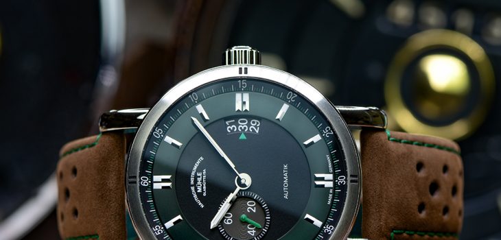 Armbanduhr Teutonia Sport II "Racing Green" am braunen Lederband liegt seitlich auf einem Stück Leder.