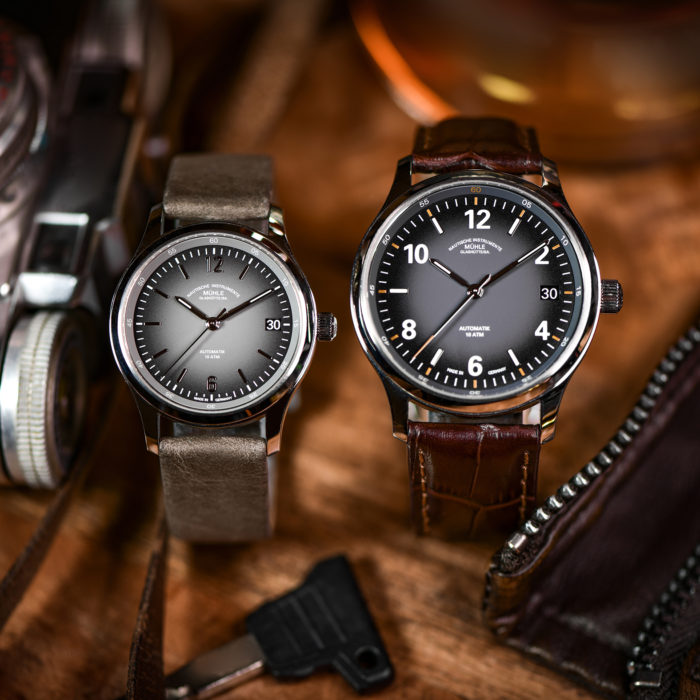 Zwei Armbanduhren (Lunova Lady am grauen Lederband und Lunova Datum am braunen Lederband) stehen auf einem Holztisch.