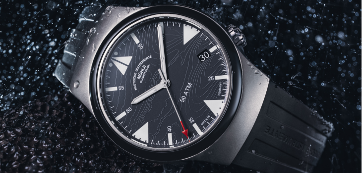 Armbanduhr S.A.R. Mission-Timer "160 Jahre DGzRS" am schwarzen Kautschukband liegt leicht schräg auf einer schwarzen Oberfläche im Regen.