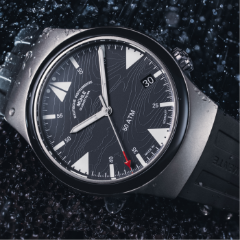 Armbanduhr S.A.R. Mission-Timer "160 Jahre DGzRS" am schwarzen Kautschukband liegt leicht schräg auf einer schwarzen Oberfläche im Regen.