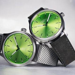 Zwei Armbanduhren (Panova Limettengrün am Milanaiseband und Panova Limettengrün am grauen Veloursband) liegen übereinander auf einer hellgrauen Oberfläche.
