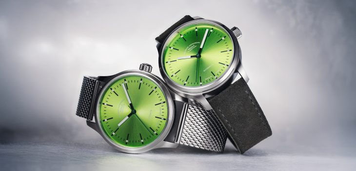 Zwei Armbanduhren (Panova Limettengrün am Milanaiseband und Panova Limettengrün am grauen Veloursband) liegen übereinander auf einer hellgrauen Oberfläche.