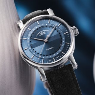 Die Teutonia II Ringdatum in graublau lehnt gegen ein Objekt vor blauem Hintergrund.