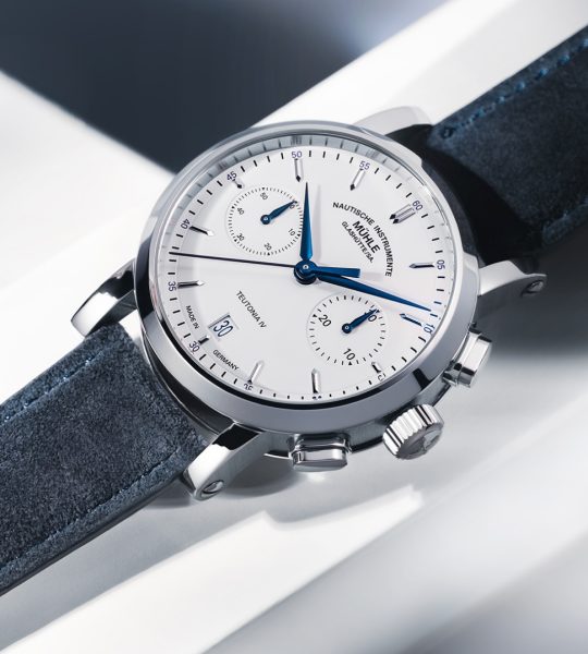 Armbanduhr Teutonia IV Chronograph mit weißem Zifferblatt, silbernem Gehäuse und blauem Velourslederband liegt auf einem weißen Untergrund.