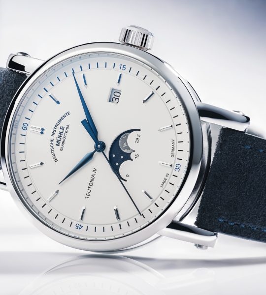 Armbanduhr Teutonia IV Mondphase mit weißem Zifferblatt, Mondphase bei 6 Uhr, im silbernen Gehäsue am blauen Velourslederband liegt seitlich auf einem weißen Untergrund.