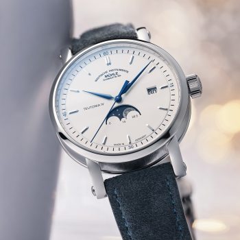 Armbanduhr Teutonia IV Mondphase am blauen Velourslederband lehnt leicht schräg an einer weißen Fläche.