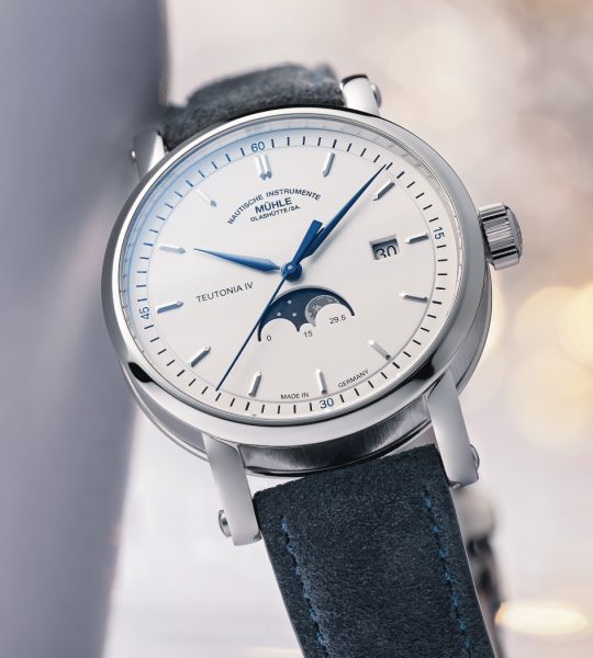 Armbanduhr Teutonia IV Mondphase am blauen Velourslederband lehnt leicht schräg an einer weißen Fläche.